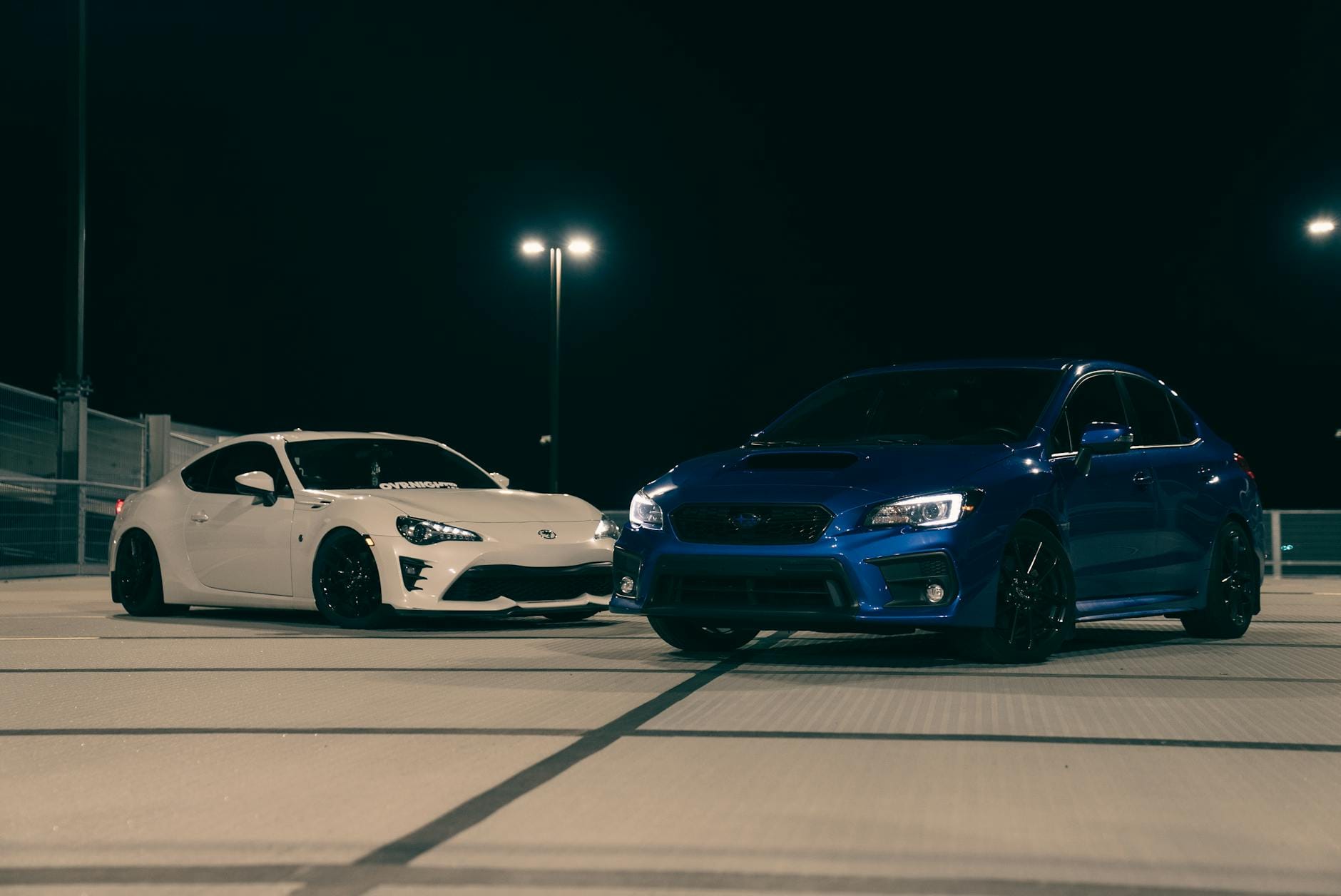 Białe i niebieskie auto sportowe zaparkowane nocą na dachu parkingu Białe i niebieskie auto sportowe zaparkowane nocą na dachu parkingu