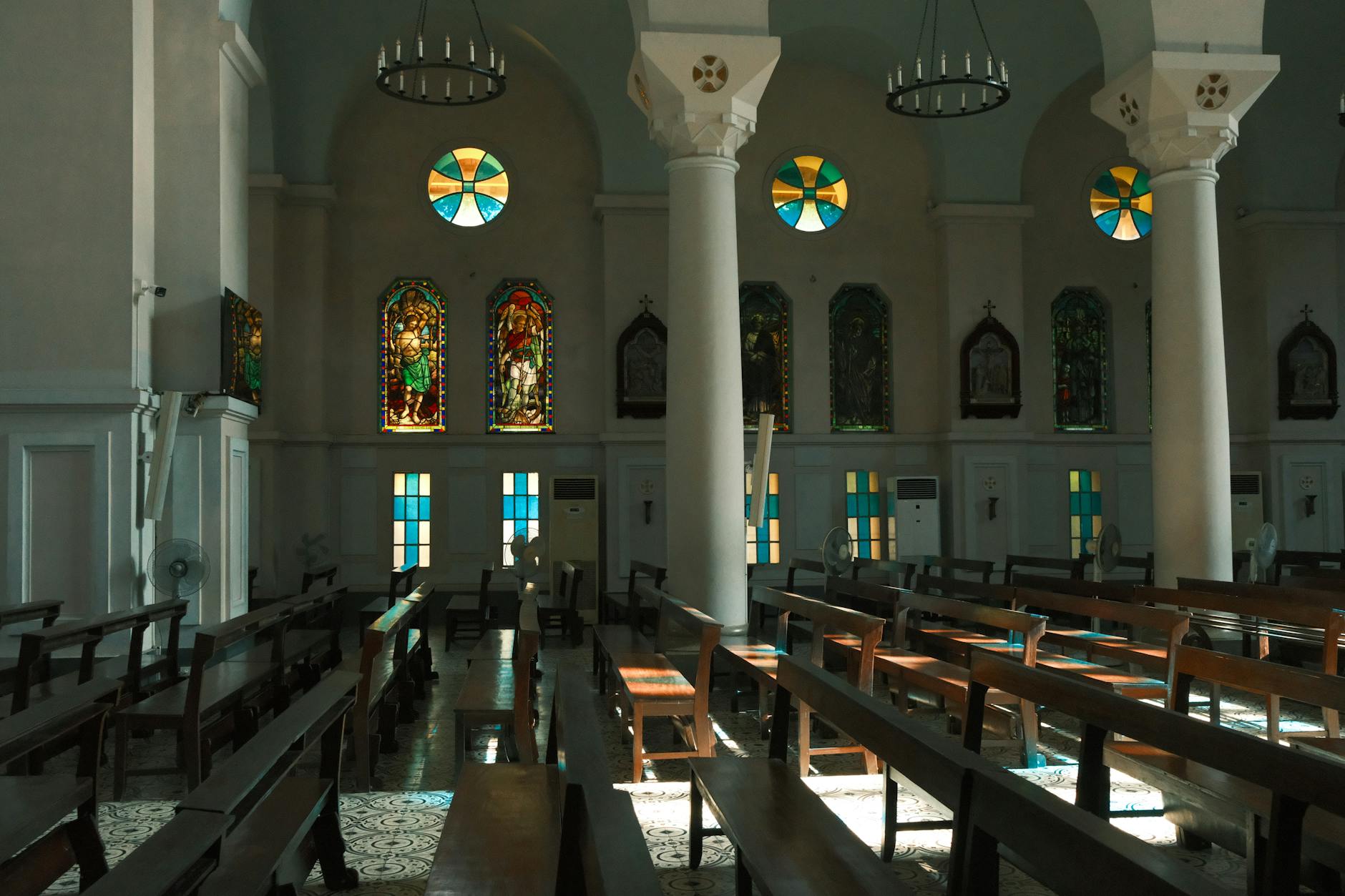 Wnętrze kościoła oświetlone słońcem z kolorowymi witrażami i ławkami