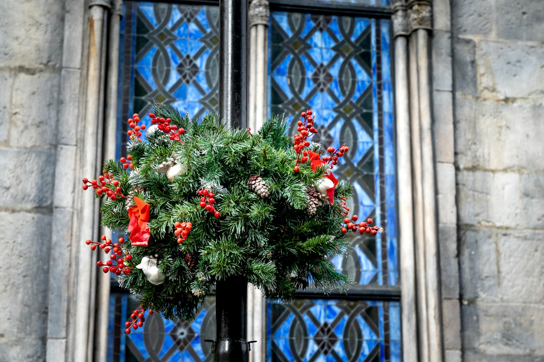 Świąteczny wieniec z szyszkami na tle kolorowego witrażu