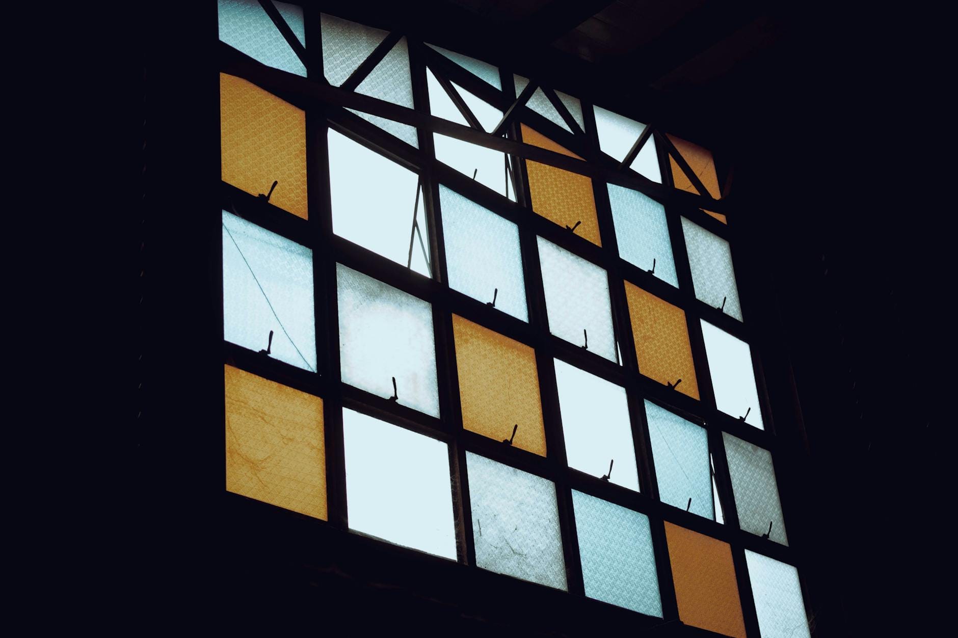 Geometryczny witraż w ciepłych barwach w przyciemnionej łazience