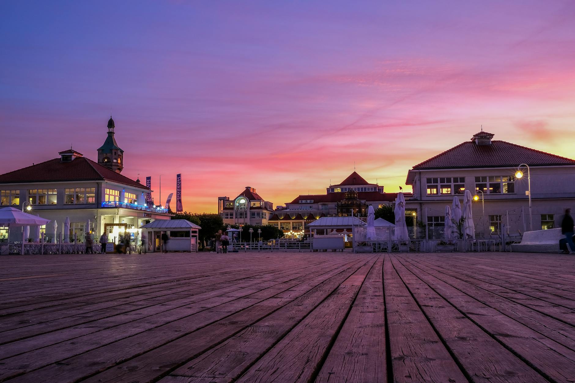 Molo w Sopocie o zachodzie słońca z historycznymi budynkami w tle