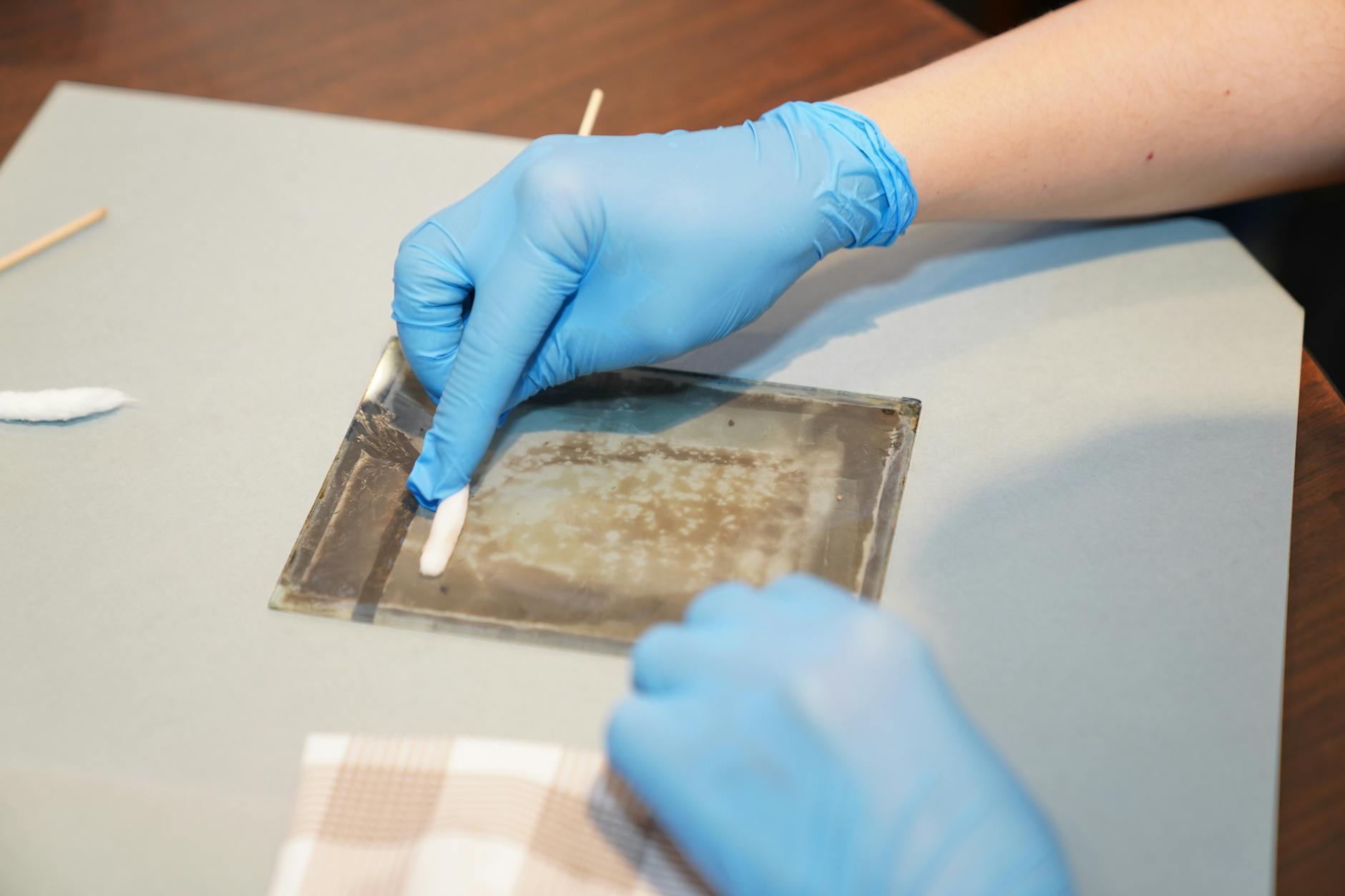 Ręce w rękawiczkach delikatnie czyszczą szklaną pracę fusingową